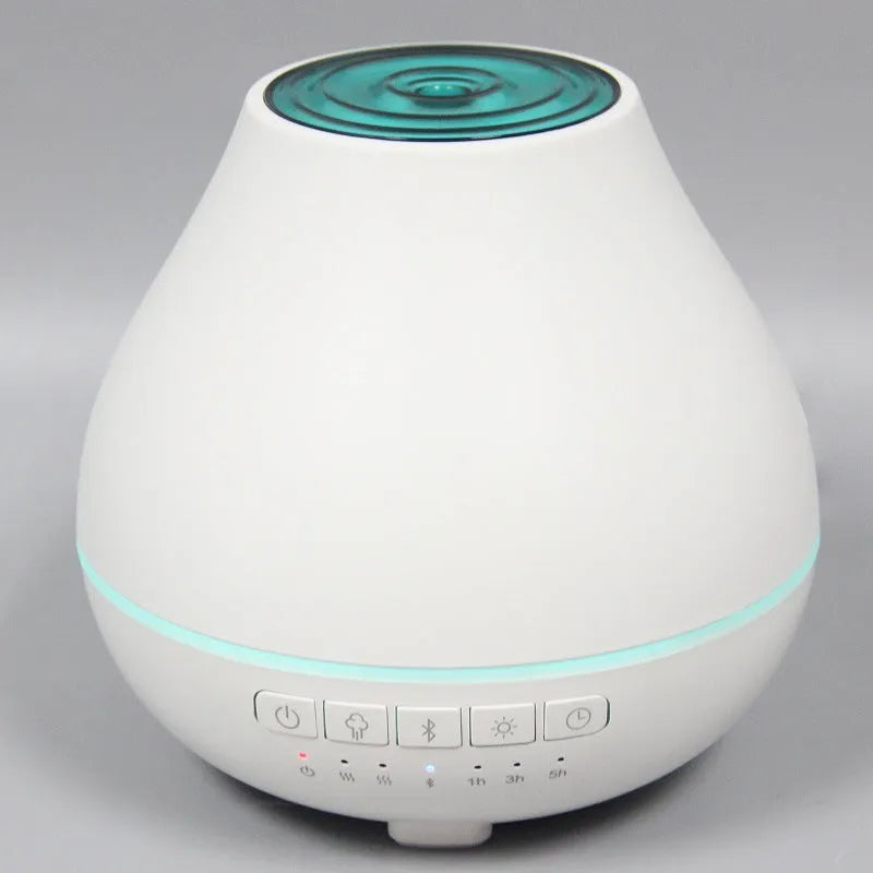 Round white Bluetooth humidifier and essential oil diffuser with night light on a wooden surface.