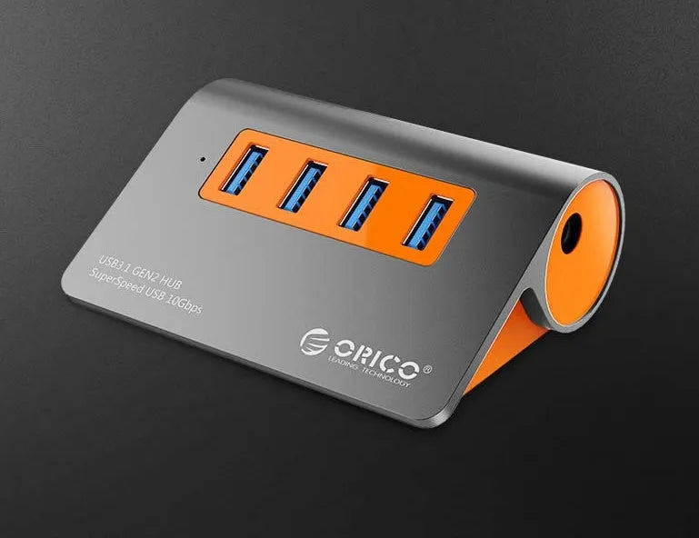 Dark grey and orange aluminium USB C hub with four USB 3.1 ports and a long black data cable.