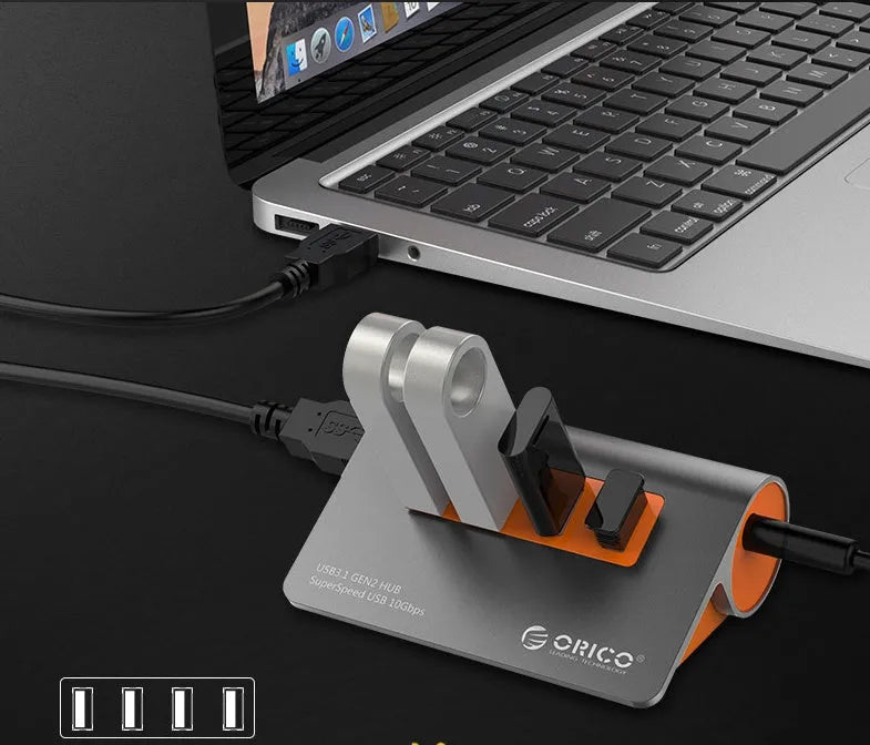 Dark grey and orange aluminium USB C hub with four USB 3.1 ports and a long black data cable.