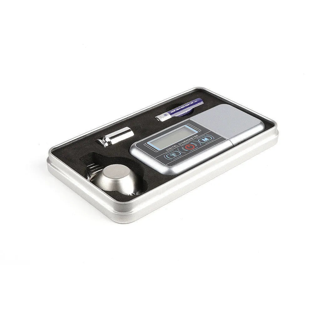 Compact black electronic gram scale with digital display on a table.