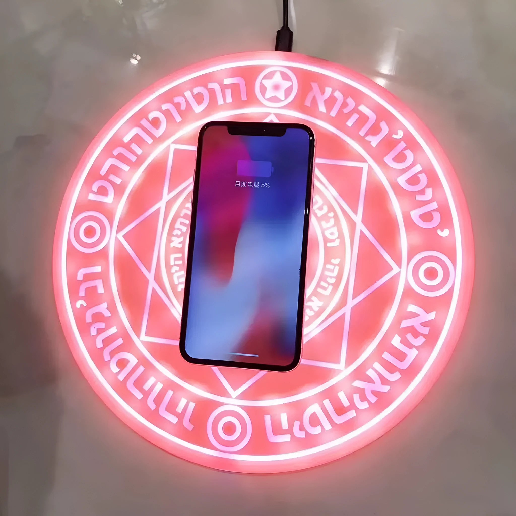 Square wireless charger with glowing magic array pattern design showing phone charging placement