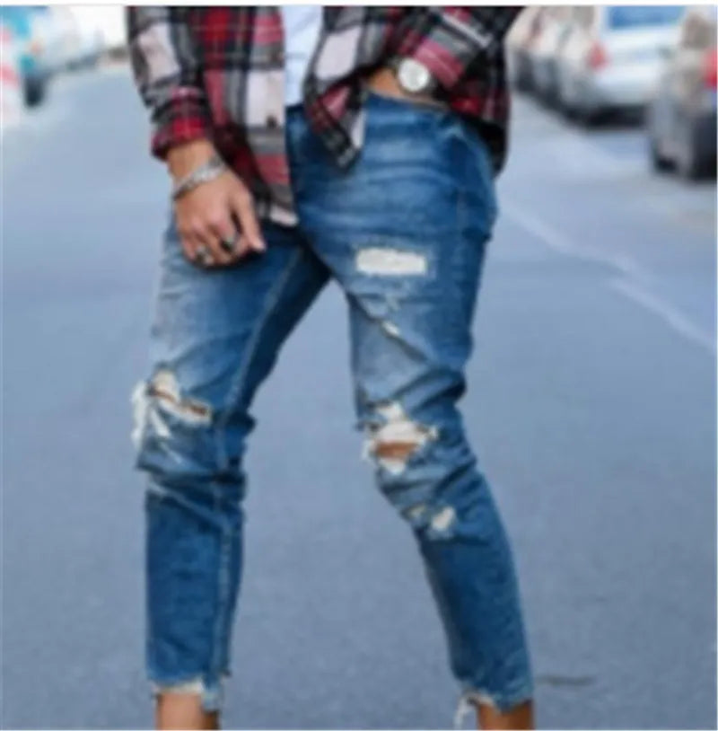 Deep blue men's jeans with distressed holes on the knees, laid flat.