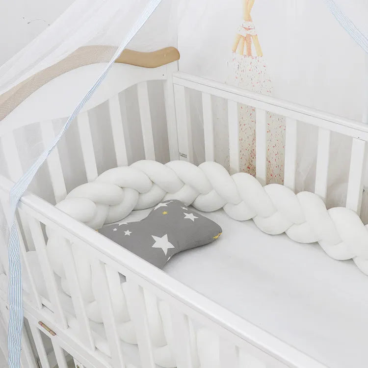 Braided knot pillow cushion bumper for infant crib in spandex velvet, shown in a light colour.