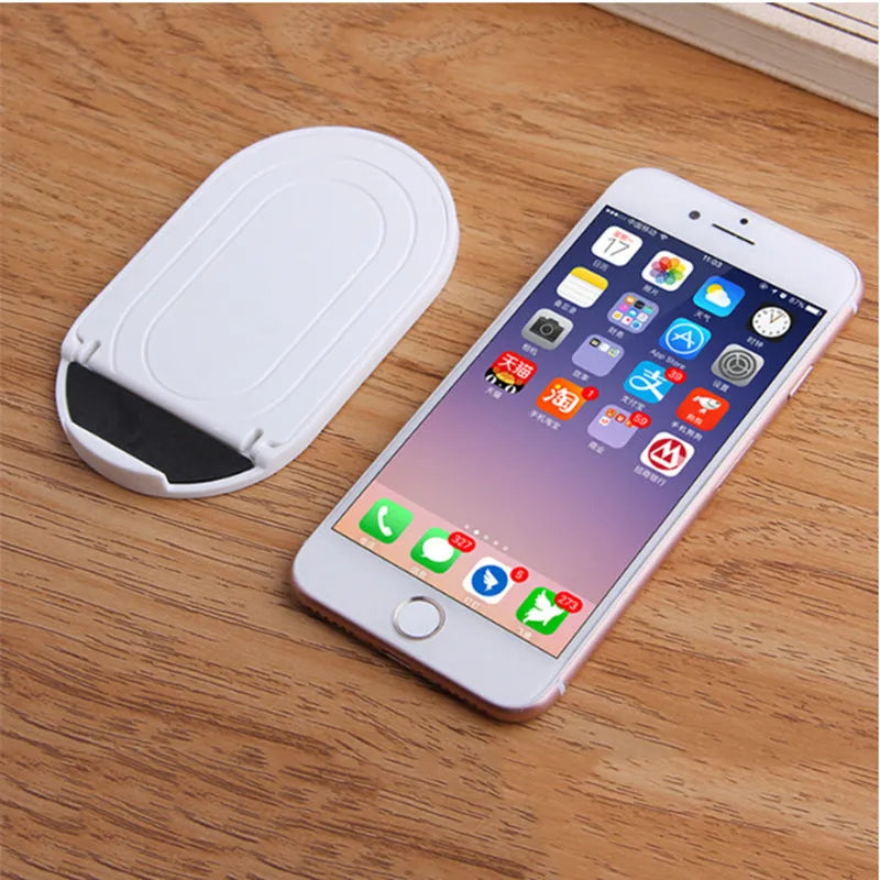 Plastic adjustable bracket mobile phone stand in six colour choices on a desk.