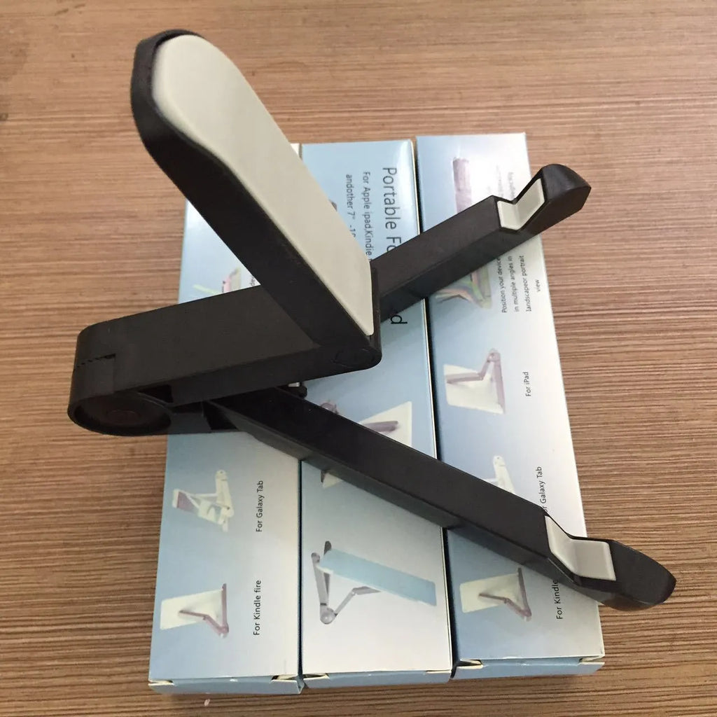 Black foldable tablet holder standing upright with a tablet in landscape mode on a wooden desk