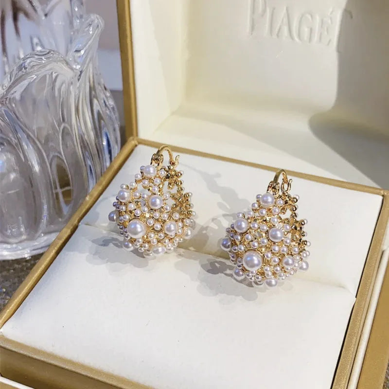 Gold tone copper flower basket earrings with small rice-shaped beads and a central pearl inlay.