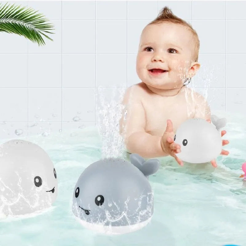 Whale-shaped baby bath toy with automatic water spray and colourful lights floating in water.