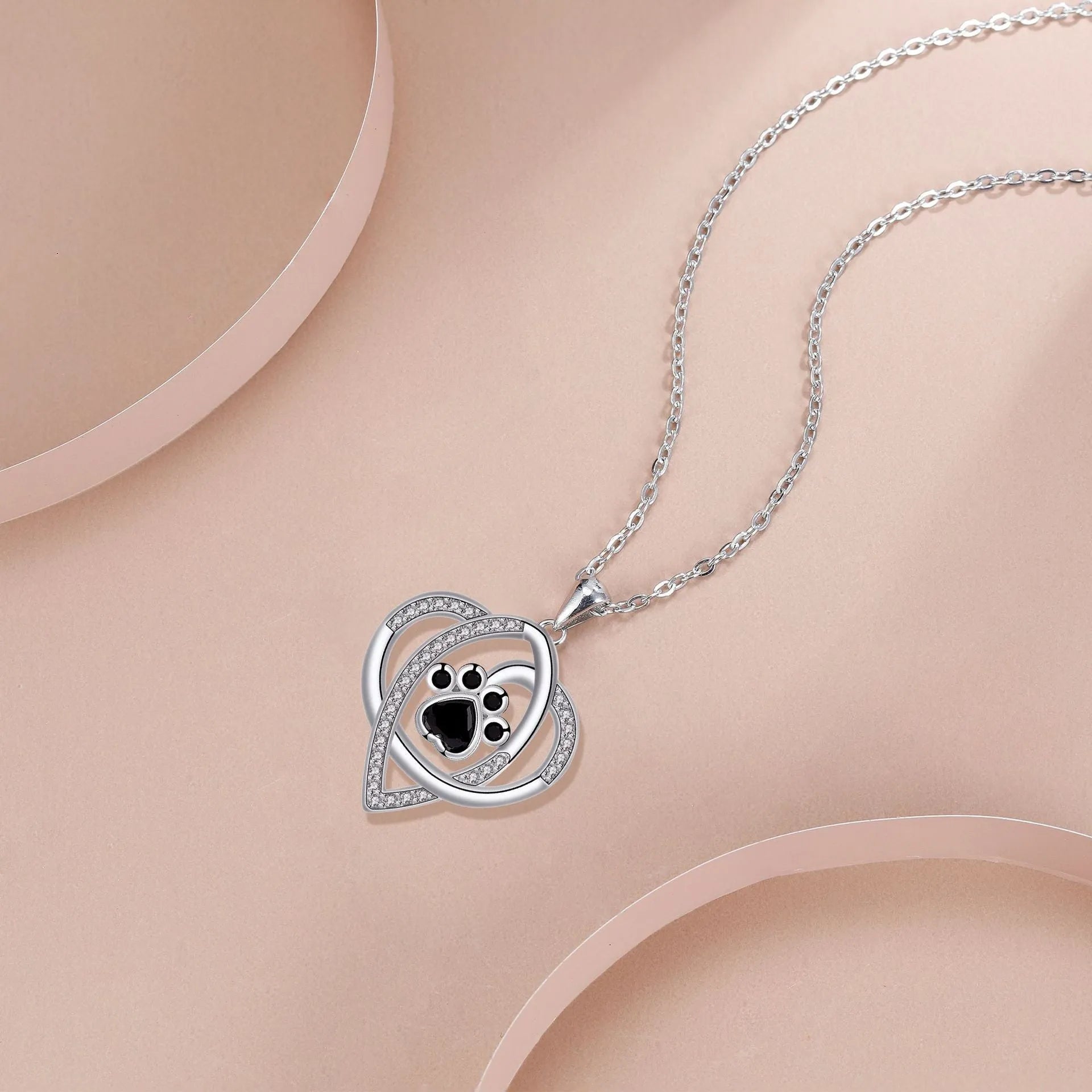 Close-up of a dog's paw print copper pendant necklace on a cross chain.