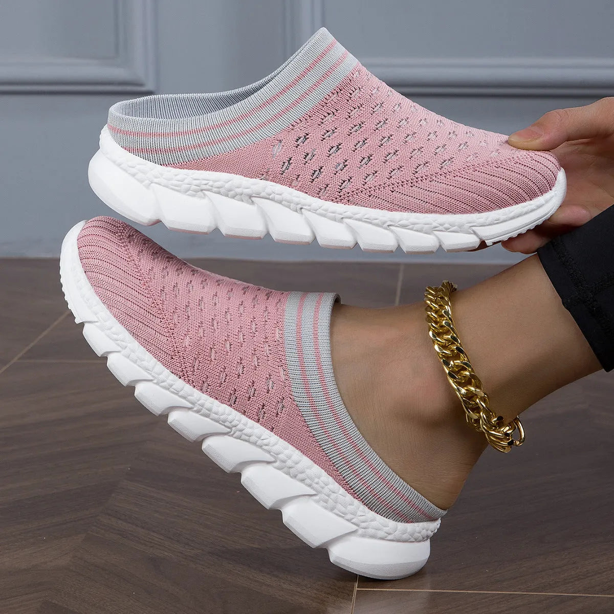 Black women's Flyknit sports slipper with hollowed-out pattern and striped design on a light background.