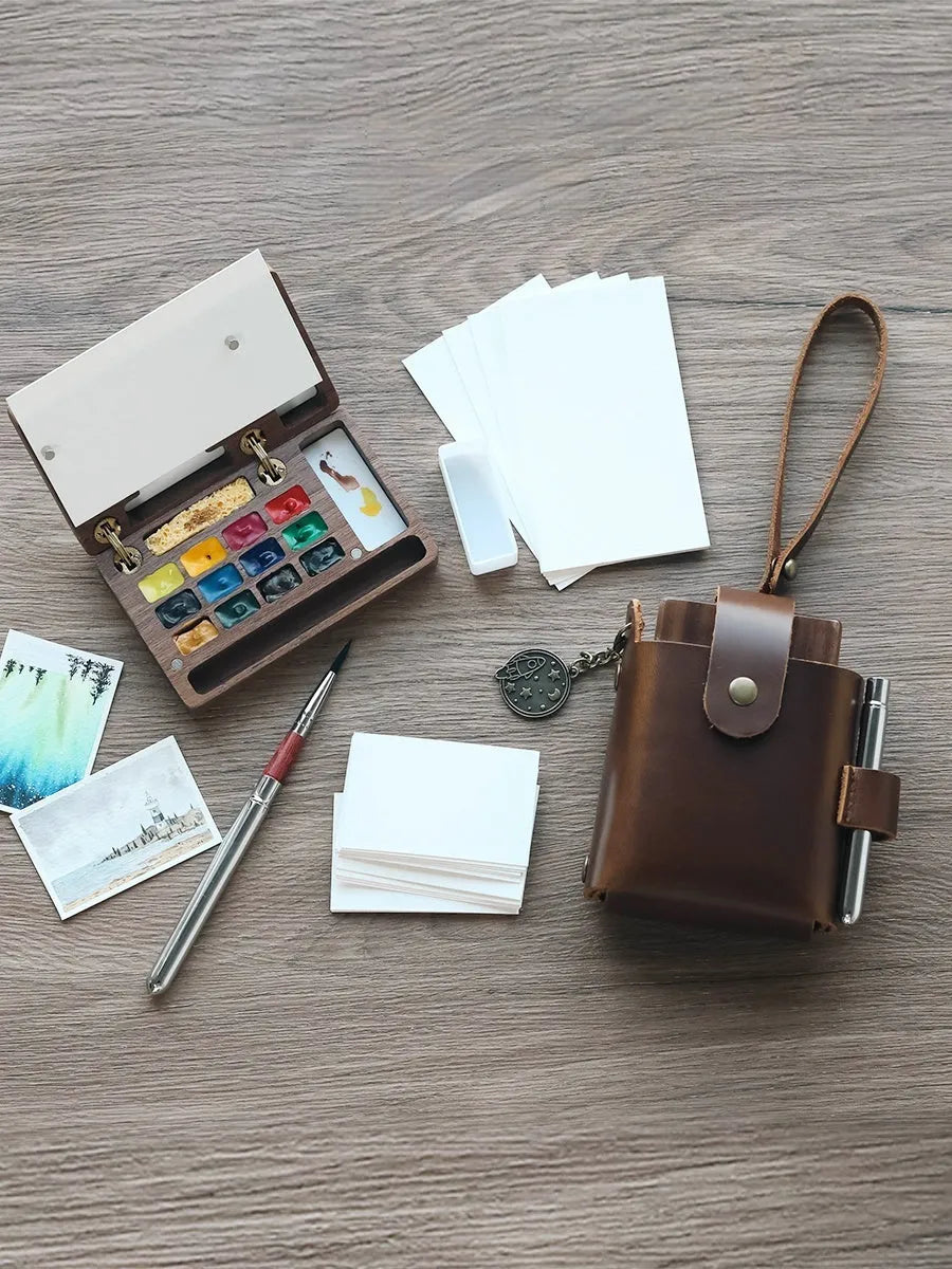Mini walnut wooden box open to show watercolour paint pans in a portable artist travel set.