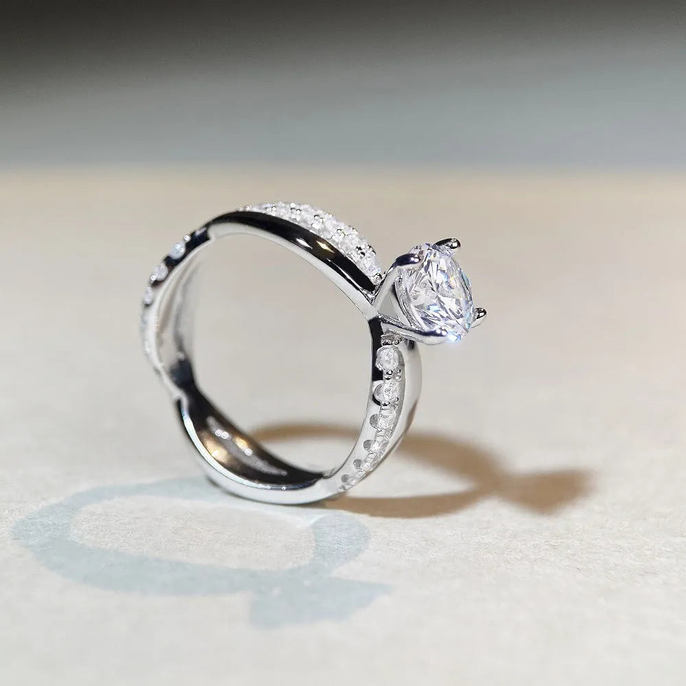 Silver ring with a 1 karat moissanite stone in a four-claw setting and a geometric twisted arm band.