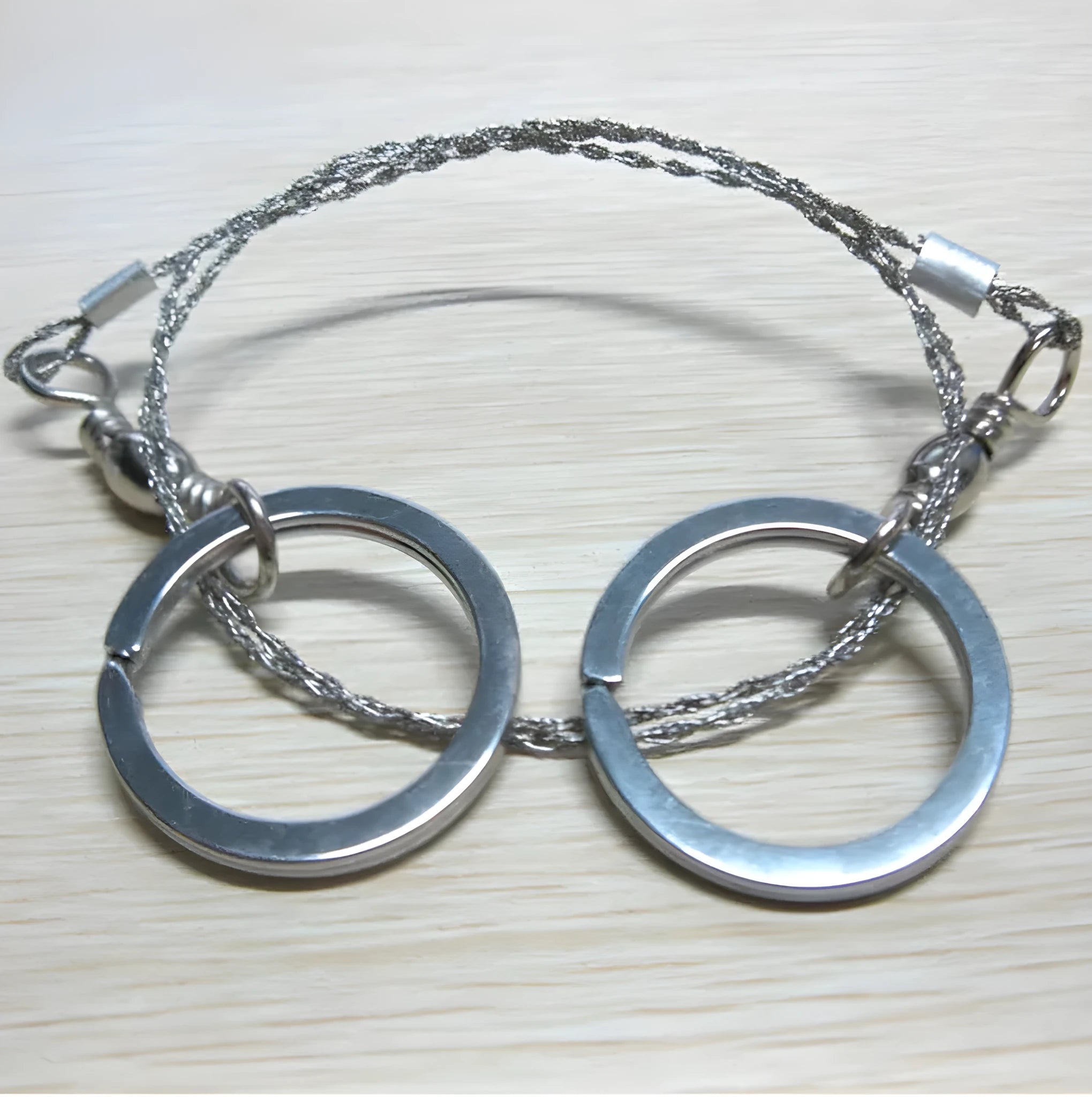 Stainless steel survival wire saw with thumb rings, extended to show its 70cm length.
