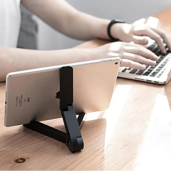 Black foldable tablet holder standing upright with a tablet in landscape mode on a wooden desk