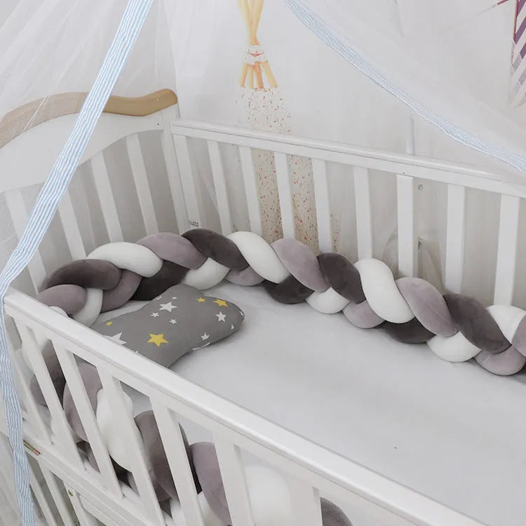 Braided knot pillow cushion bumper for infant crib in spandex velvet, shown in a light colour.