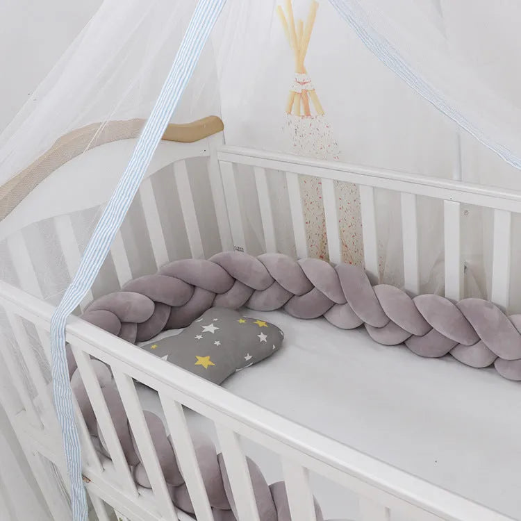 Braided knot pillow cushion bumper for infant crib in spandex velvet, shown in a light colour.