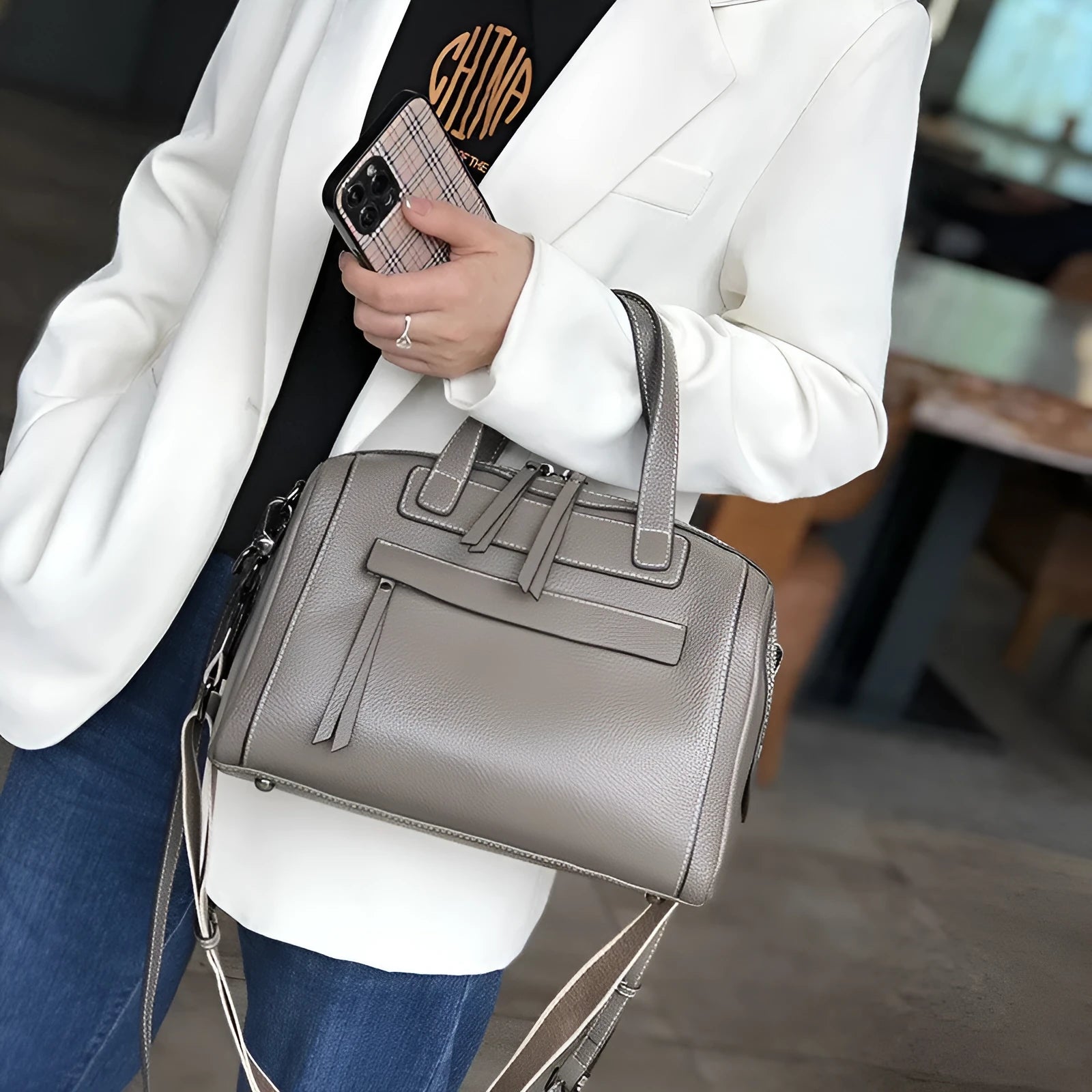 Soft black cowhide leather messenger bag with lychee pattern, showing internal phone and camera pockets.
