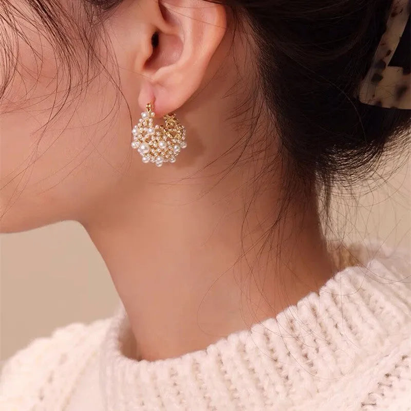 Gold tone copper flower basket earrings with small rice-shaped beads and a central pearl inlay.
