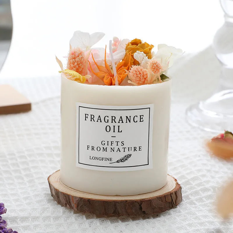Decorative scented candle with dried flowers inside, shown with wooden chip base and gift box packaging.