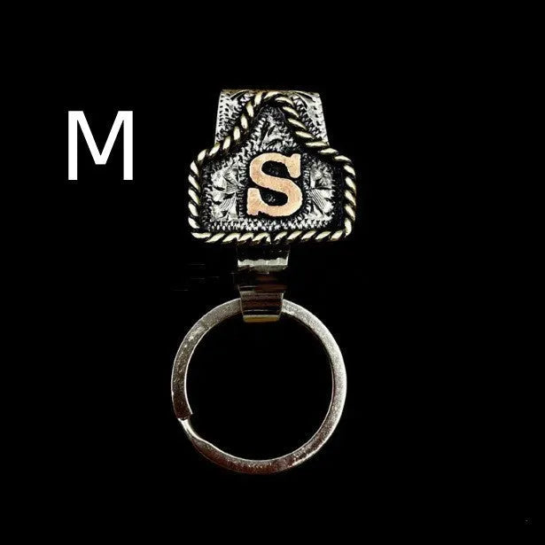 Handmade metal cow tag belt keychain showing one of 26 colour options, each marked with a different alphabet letter.