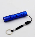 Black aluminium mini LED flashlight on a table showing its 9.5 cm length and 2 cm diameter.