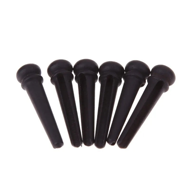 Six solid ebony guitar string nails with matt black finish for folk acoustic guitars.