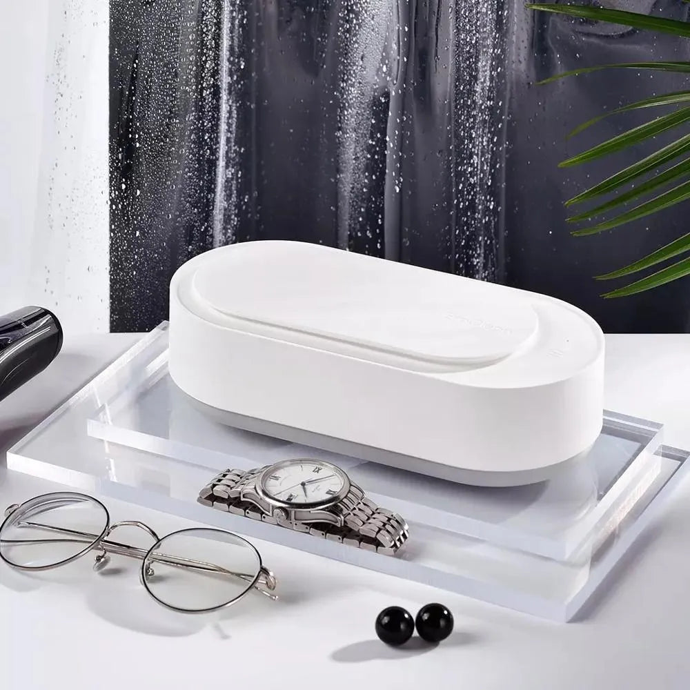 White portable ultrasonic cleaner with stainless steel tank and a single control button.