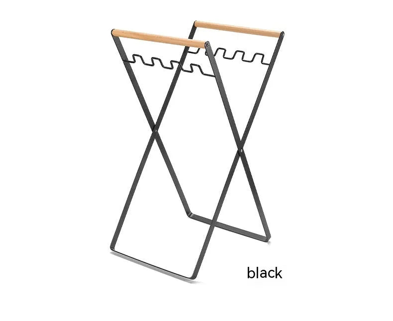 Black folding outdoor trash rack with wooden handle standing on a patio.