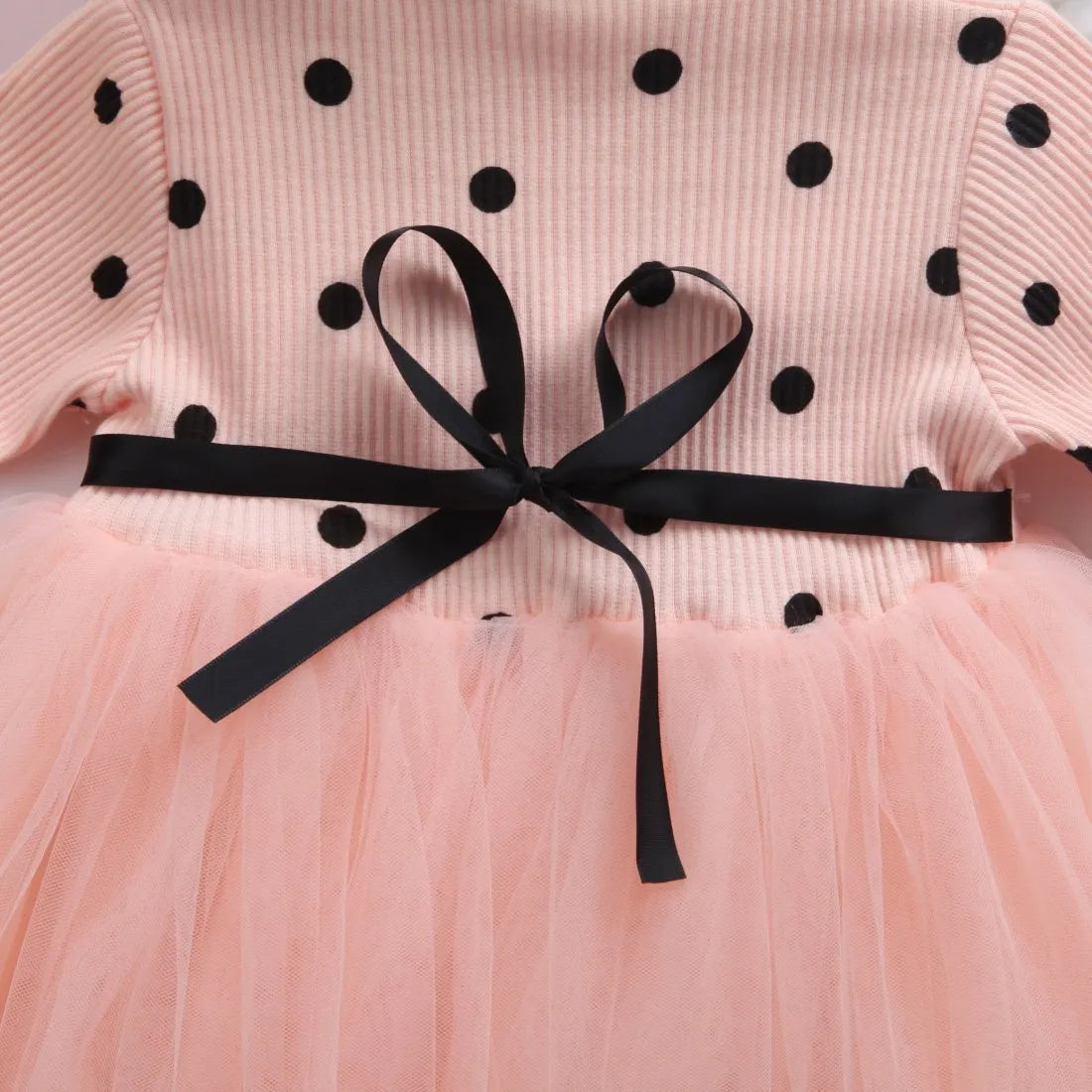 Baby girl wearing a long sleeve black tutu lace dress for a first birthday or christening event.