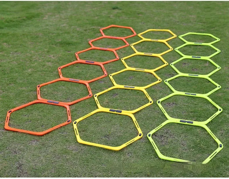 Set of six foldable yellow green and orange hexagon football agility training rings on grass