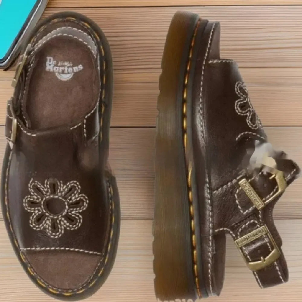Men's black embroidered floral beach sandals with flat heel on a sandy background.