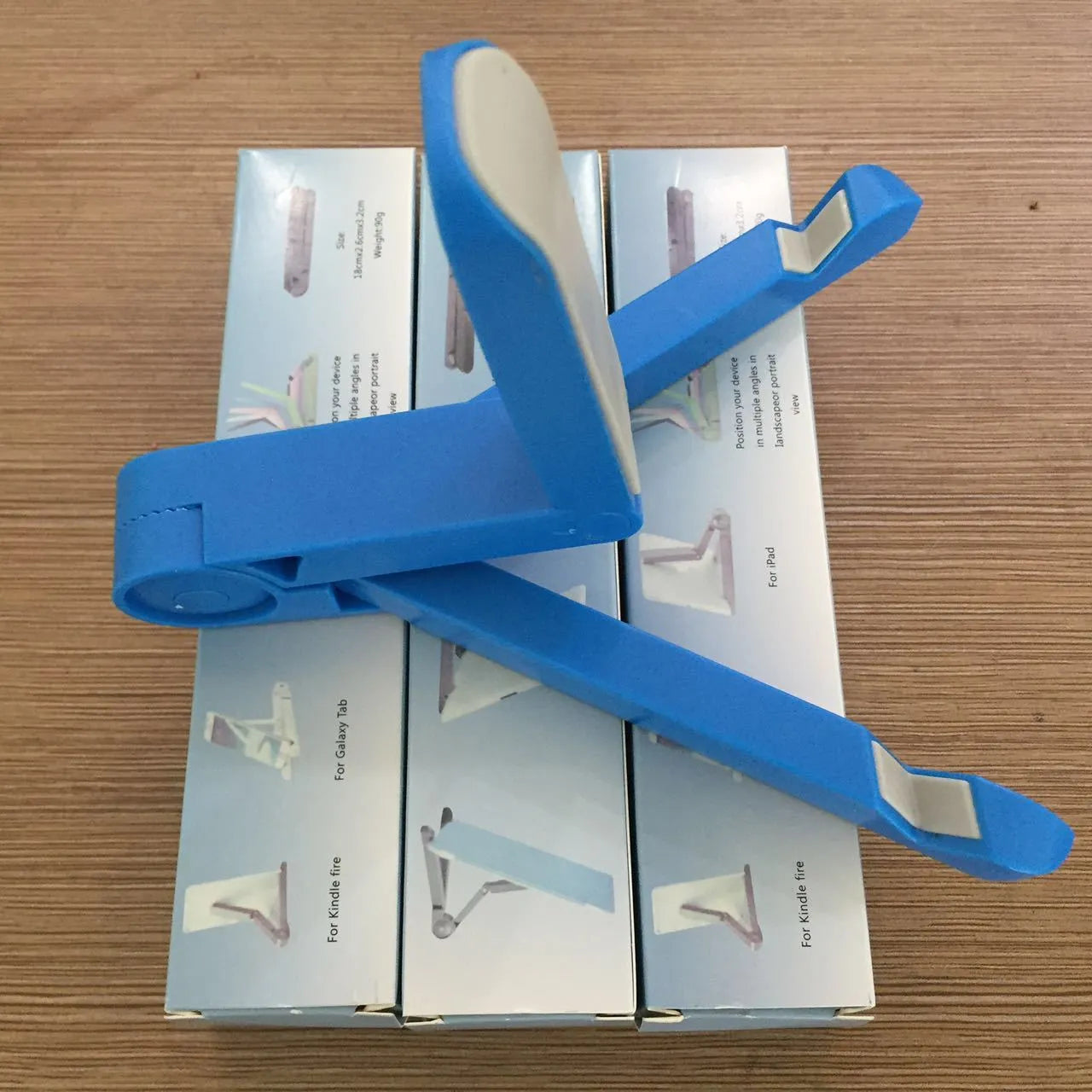 Black foldable tablet holder standing upright with a tablet in landscape mode on a wooden desk