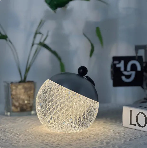 Small portable dimmable night lamp in chrome finish on wooden bedside table