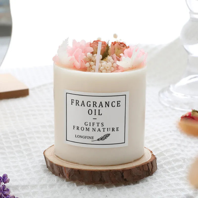 Decorative scented candle with dried flowers inside, shown with wooden chip base and gift box packaging.