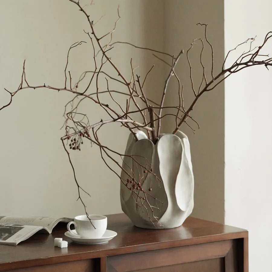 Irregular shaped handcrafted ceramic vase on a wooden surface, showing its artisanal form.