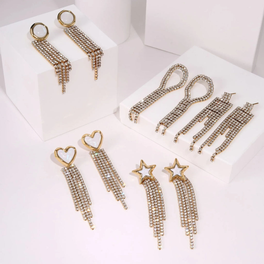 Close-up of a women's stainless steel earring with a heart shape and a dangling geometric tassel featuring diamond and star details.