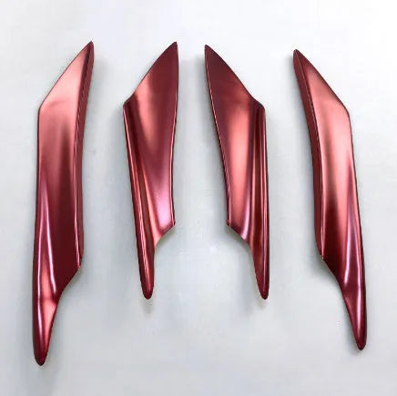 Set of four carbon fibre pattern bumper blade spoilers for car modification on a black background.