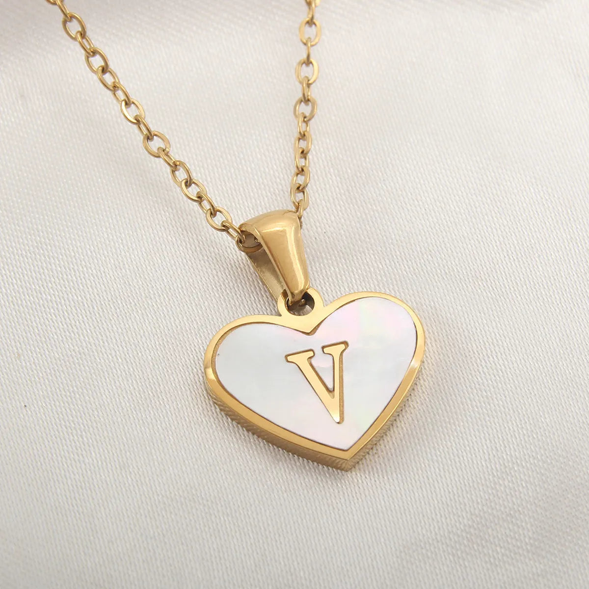 Gold-plated heart necklace with white shell pendant showing initial engraving on stainless steel chain