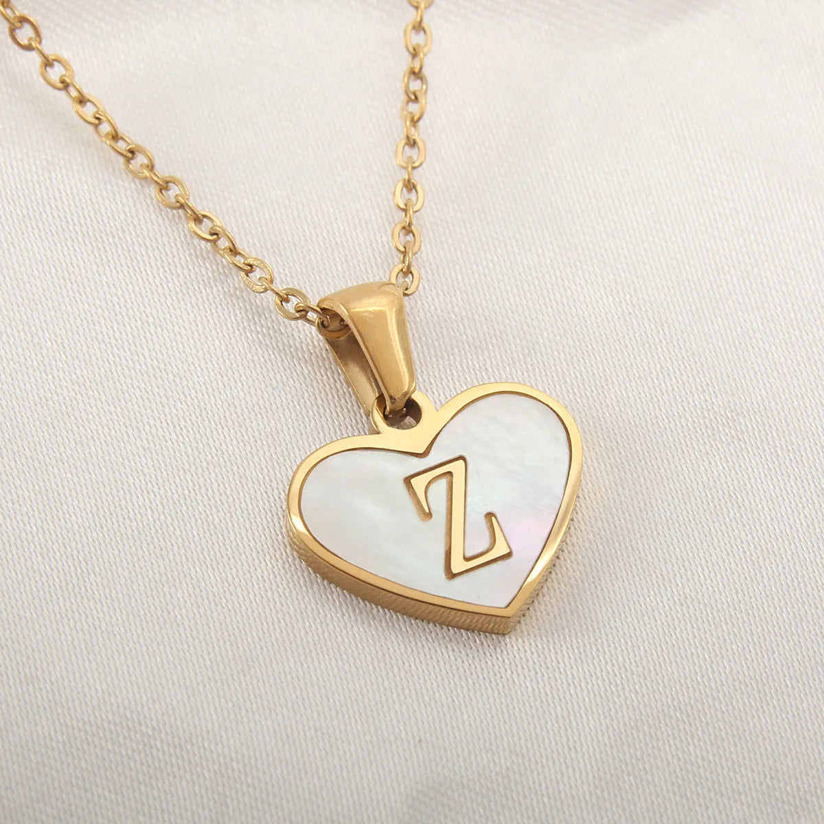 Gold-plated heart necklace with white shell pendant showing initial engraving on stainless steel chain