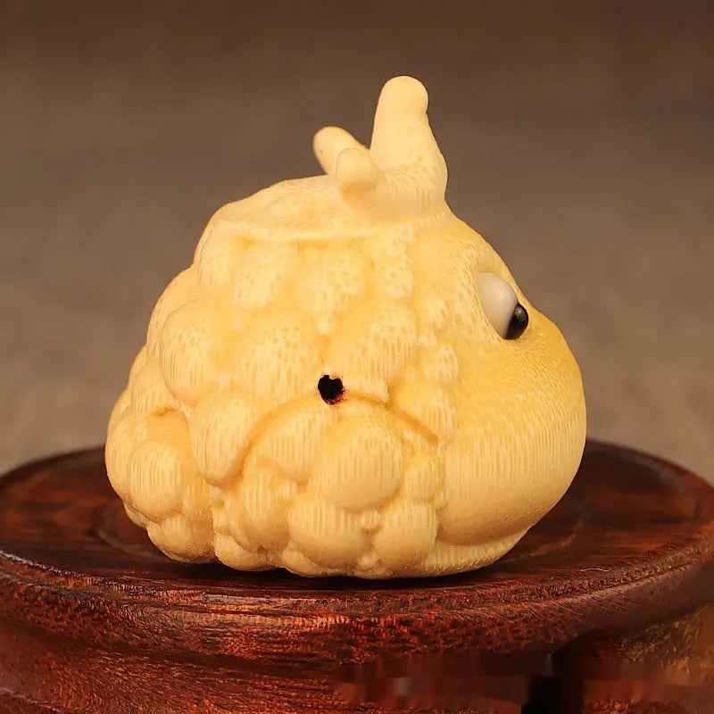 Solid bamboo carving of a cute Crown Princess toad ornament on a wooden surface.