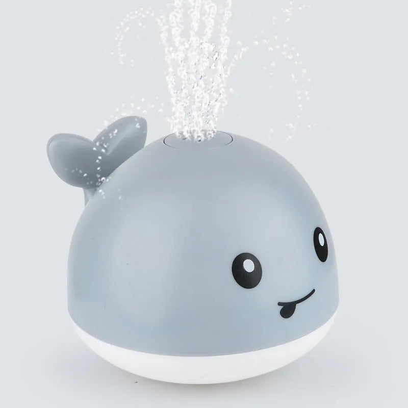 Whale-shaped baby bath toy with automatic water spray and colourful lights floating in water.