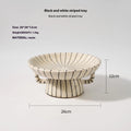 Black and white striped plastic resin fruit plate on a wooden surface.