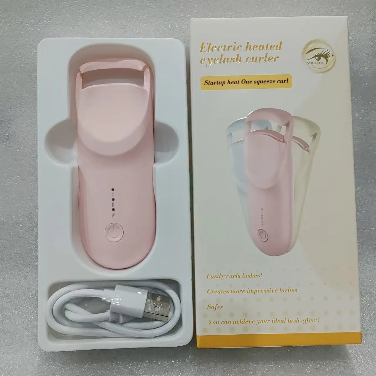 USB electric eyelash curler in cream white, pink, or apricot with charging cable.