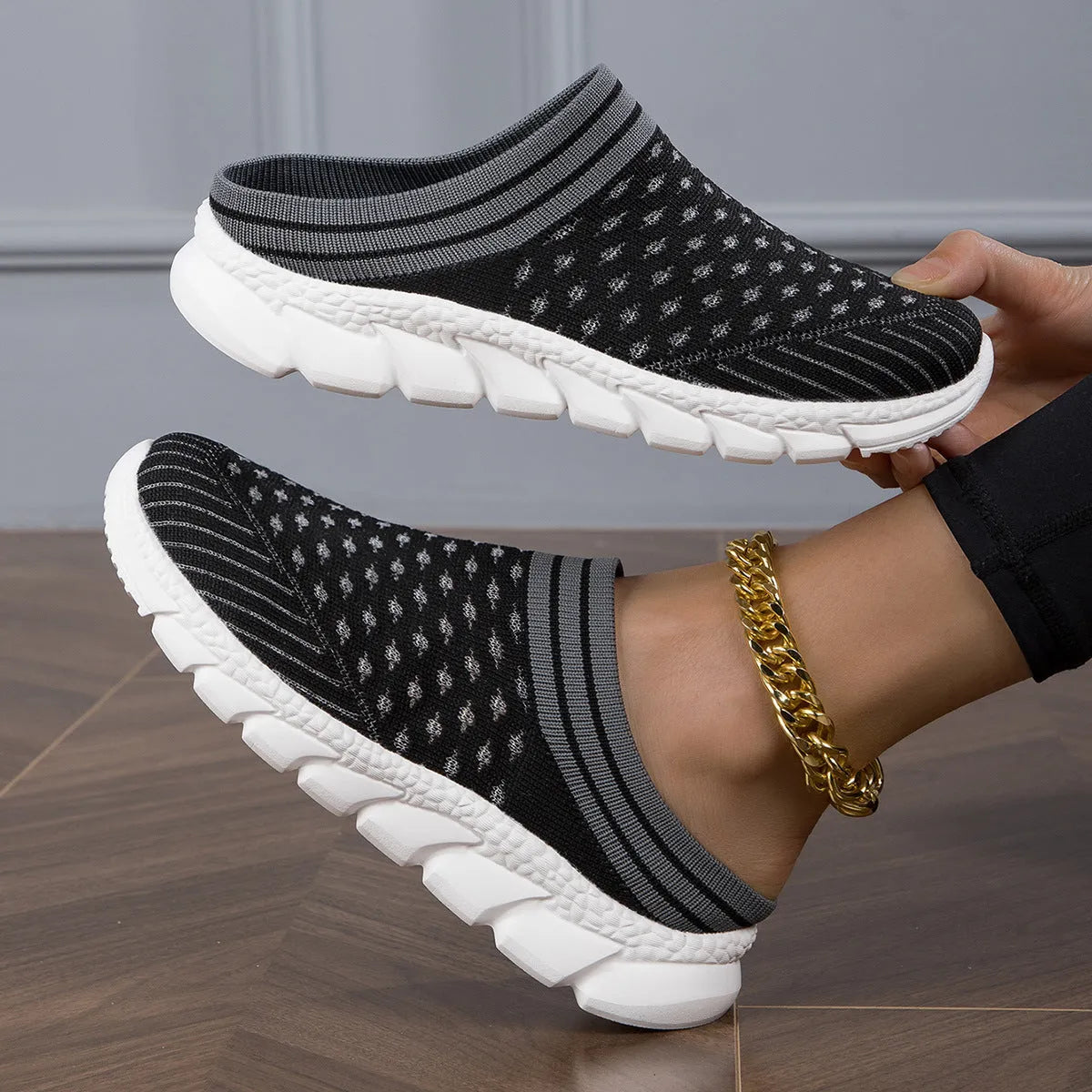 Black women's Flyknit sports slipper with hollowed-out pattern and striped design on a light background.