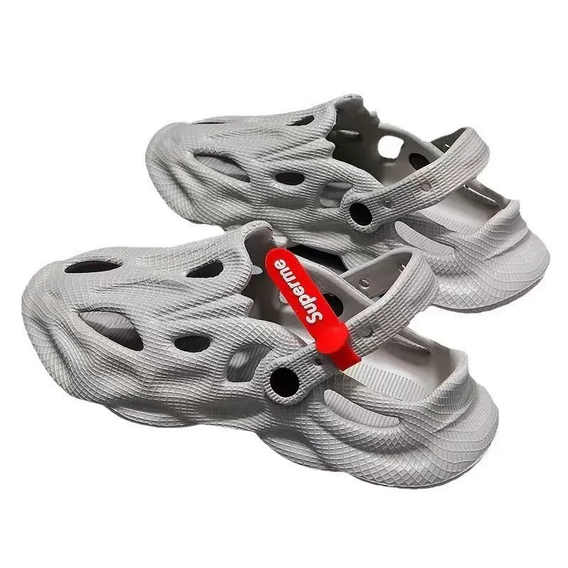 Men's grey EVA foam slippers with closed toe and thickened sole on a sandy beach.