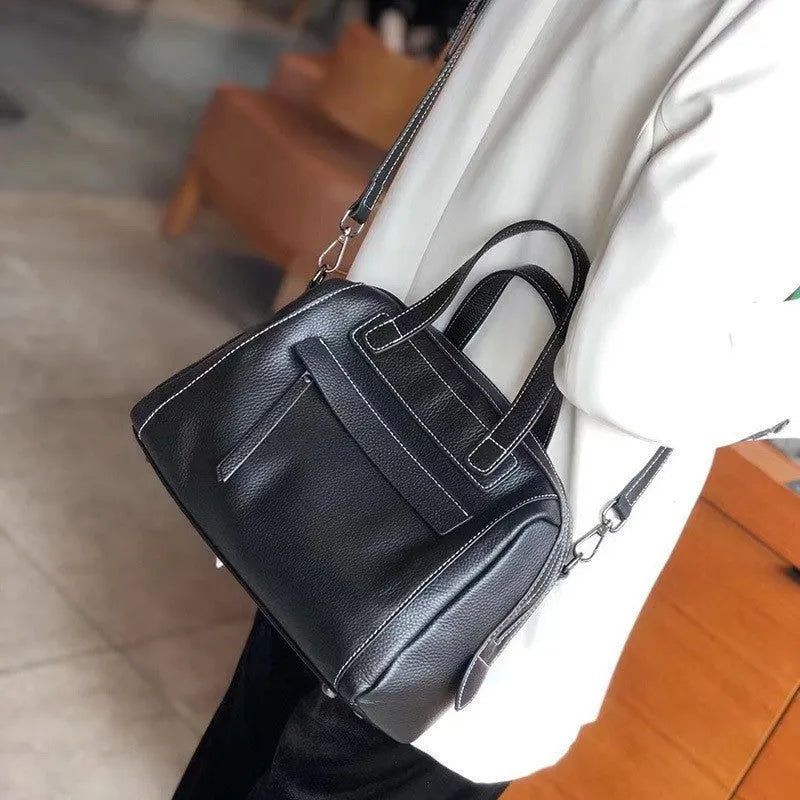 Soft black cowhide leather messenger bag with lychee pattern, showing internal phone and camera pockets.