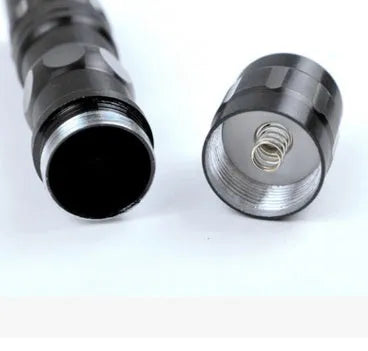 Black aluminium mini LED flashlight on a table showing its 9.5 cm length and 2 cm diameter.