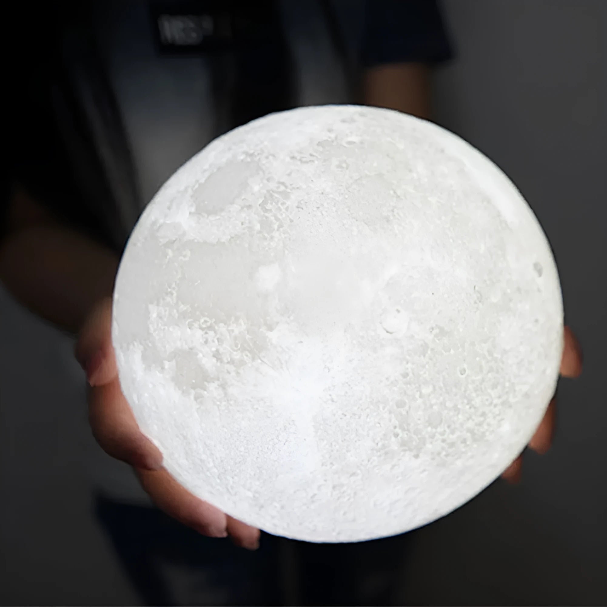 3D printed white moon lamp on wooden stand showing detailed lunar surface texture.