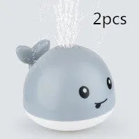 Whale-shaped baby bath toy with automatic water spray and colourful lights floating in water.
