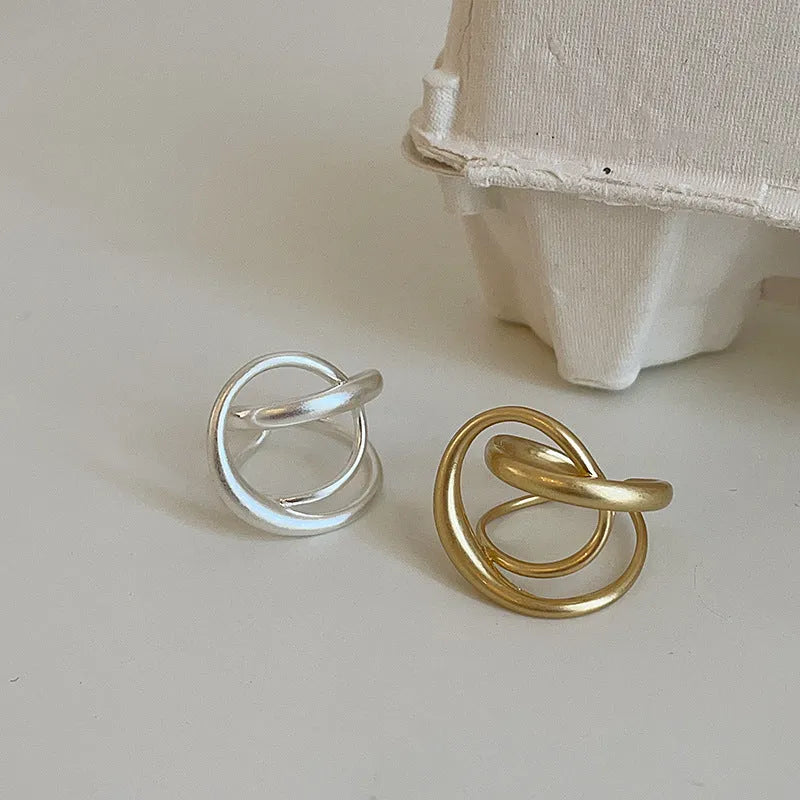 Geometric open ring for women with 3D interlaced matte metal design, shown in gold plating.