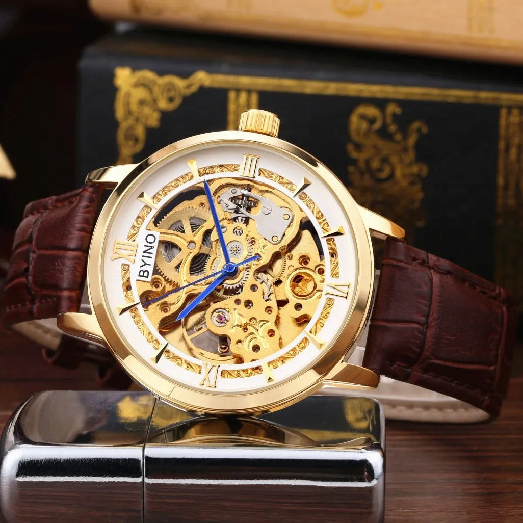Men's automatic mechanical watch with skeleton dial, leather strap, and gold-tone case on a neutral background